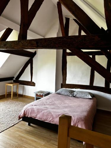 a bed in a room with wooden beams at La maison des Graviers in Nogent-sur-Seine