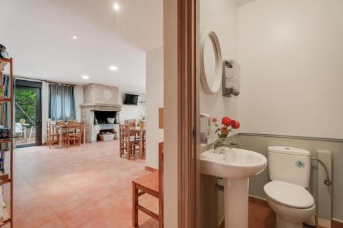 a bathroom with a sink and a toilet and a living room at Sueños de Guara Casa rural in Casbas de Huesca