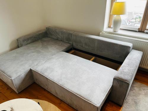 a gray couch in a room with a window at Stilvolle Studiowohnung mit Sonnenterasse in Rheda-Wiedenbrück