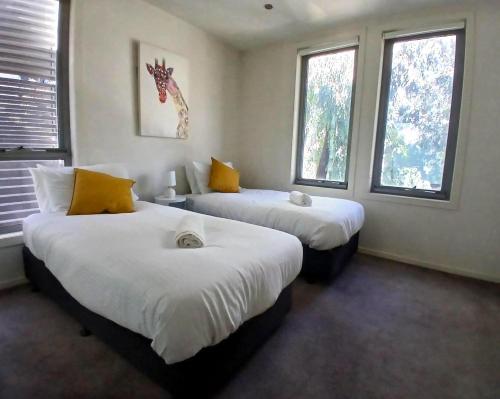 two beds in a room with two windows at Docklands Serenity in Melbourne