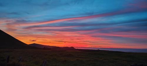 a sunset over a field with a mountain in the background at Lodge Hare Ariki Koreto in Hanga Roa