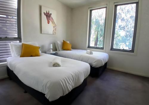 two beds in a room with two windows at Docklands Serenity in Melbourne