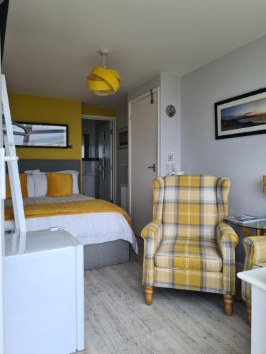 a bedroom with a bed and a chair at Sirens Sunset Peaceful Retreat with stunning sea views, 5 minutes from Porth Beach in Newquay