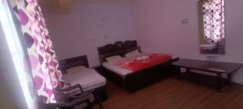 a small room with a bed and a table and a window at Hotel The Tragopan in Sarāhan