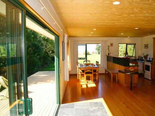 a kitchen and dining room with a sliding glass door at Tomatea Rua - Golden Bay Bach Pakawau Beach in Pakawau