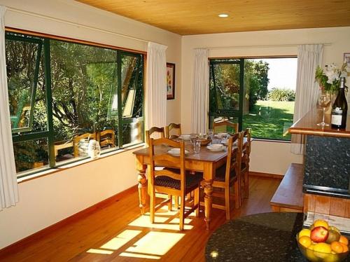 a dining room with a table and some windows at Tomatea Rua - Golden Bay Bach Pakawau Beach in Pakawau