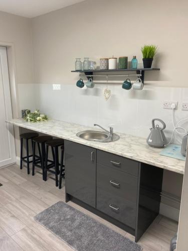 a kitchen with a sink and a counter with stools at Serenity Ballycastle in Ballycastle
