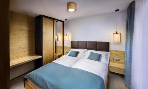 a bedroom with a bed with blue and white sheets at APLEND Monte Móry in Štrbské Pleso