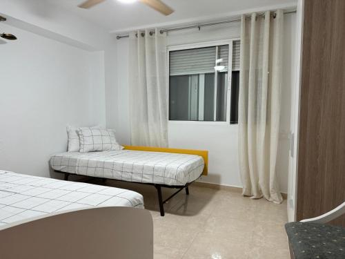 Zimmer mit 2 Betten und einem Fenster mit Vorhängen in der Unterkunft Nuevo Acapulco in San Francisco