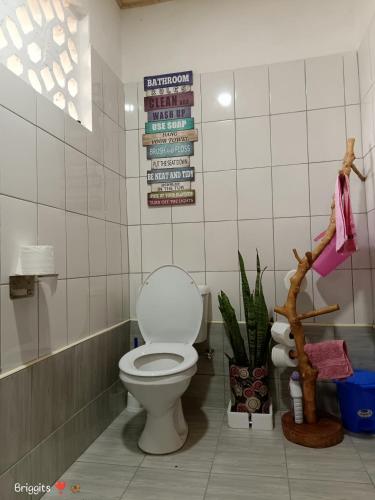 a bathroom with a toilet and signs on the wall at Hellenas Gem in Ukunda