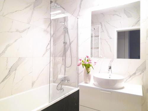 a white bathroom with a sink and a shower at Vista Residence Wola in Warsaw