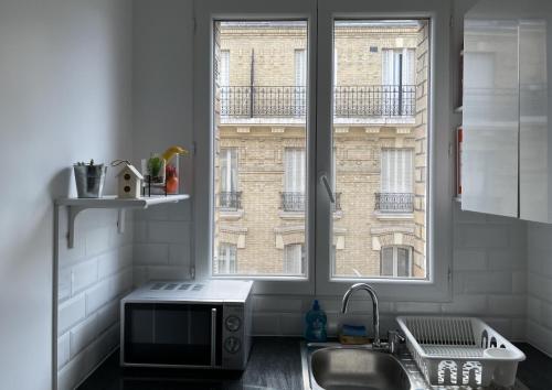 une cuisine avec un évier et une fenêtre dans l'établissement Cadre idéal, à Pantin