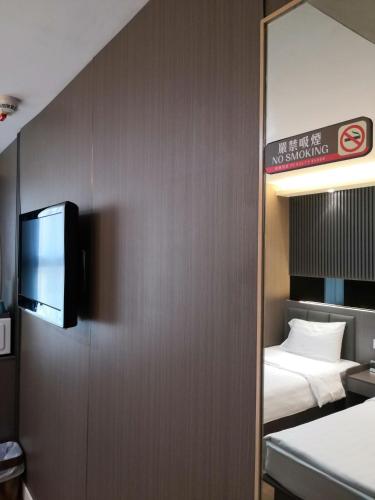 a room with a bed and a tv on a wall at Hennessy Hotel in Hong Kong