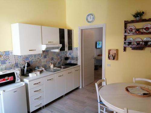 a kitchen with white cabinets and a table and a clock at Karaly - Casa vacanze posto auto/moto in Cagliari