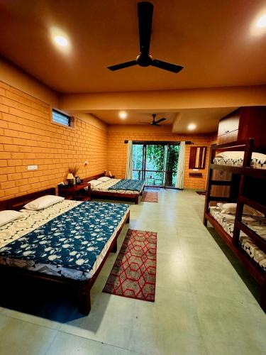 a bedroom with two beds and a ceiling fan at Sereno Barn Eco Stay Chikmagalur in Chikmagalūr
