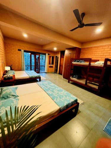 a bedroom with two beds and a ceiling fan at Sereno Barn Eco Stay Chikmagalur in Chikmagalūr
