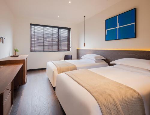 a hotel room with two beds and a window at Tan Alley Wuzhen Eco and Cultural Community in Tongxiang