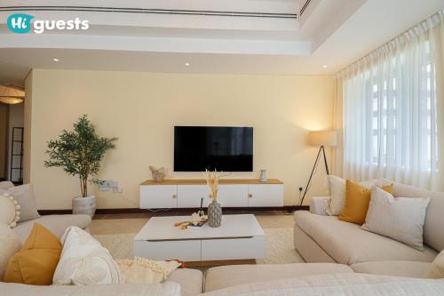 a living room with white furniture and a flat screen tv at HiGuests - Elegant Family Retreat in Dubai's Deira 3BR Oasis in Dubai