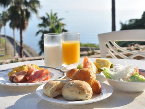 a table with two plates of food and a glass of orange juice at Hotel Alegria Gardens Amakusa - Vacation STAY 40454v in Amakusa