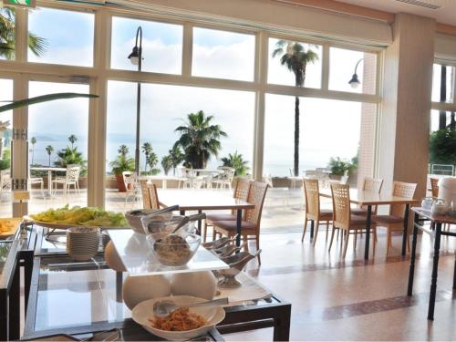 a dining room with tables and chairs and large windows at Hotel Alegria Gardens Amakusa - Vacation STAY 40454v in Amakusa