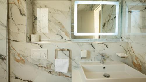a white bathroom with a sink and a mirror at F&M Hotel 2 in Tirana
