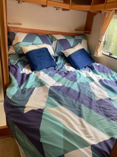 a bed with blue pillows on it in a room at Pantyronen tourer holidays in Llanbadarn-fynydd