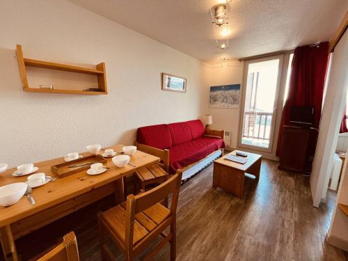 un salon avec une table et un canapé rouge dans l'établissement Appartement 2 pièces pour 5 personnes avec accès direct aux pistes et balcon – Vallandry - FR-1-757-99, à Landry