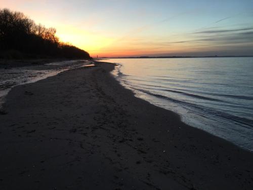 a beach at sunset with the sun setting over the water at Ferienhaus Bolliger Apartment 2 in Kalkhorst
