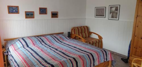 Bungalow Rose في لودين: غرفة نوم بها سرير وكرسي وبطانية مخططة