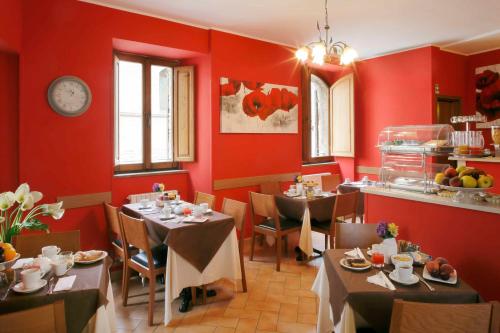 ein Restaurant mit roten Wänden und Tischen und einer Uhr in der Unterkunft Hotel Properzio in Assisi