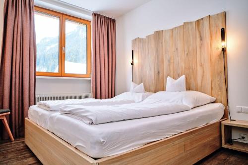 a bedroom with a large bed with a wooden headboard at Der Tannenhof in Hinterbichl