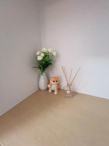 a cat sitting on the floor next to a vase with flowers at アーバンハイツ渡辺通a棟 in Fukuoka