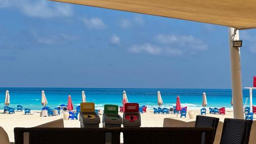 a beach with chairs and umbrellas and four parking meters at Panoramic see view apartment in North Coast الساحل الشمالي in Alexandria
