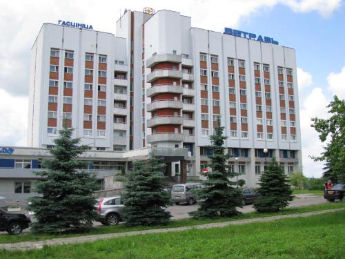 a large building with cars parked in a parking lot at Hotel Vetraz in Vitebsk