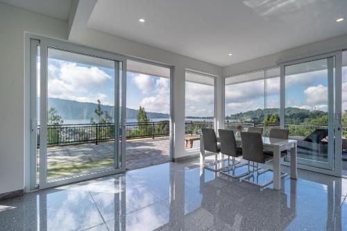 a dining room with a table and chairs and windows at Adara Lake View Residence Bedugul - Bali in Bedugul