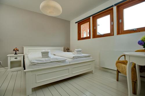 Un dormitorio blanco con una cama y dos ventanas. en Ankerlicht - Bungalow L, en Westerland