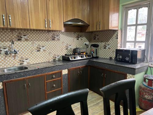 a kitchen with wooden cabinets and black chairs in it at Hamro Family Ghar Apartment or Room near Kathmandu in Kathmandu