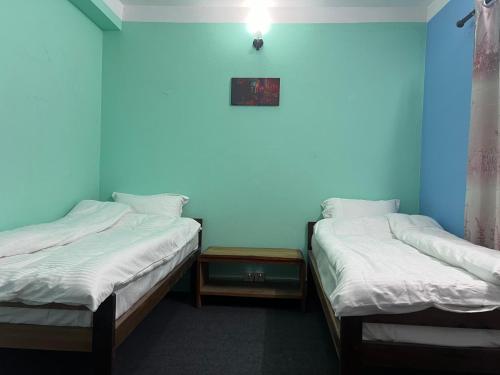 two beds in a room with blue walls at Hamro Family Ghar Apartment or Room near Kathmandu in Kathmandu