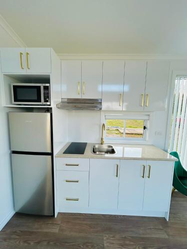 a small kitchen with white cabinets and a sink at Red Hill Cabin #1 Walcha in Walcha