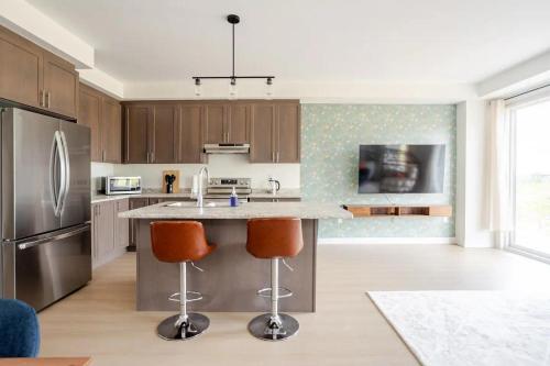 a kitchen with a large island with two bar stools at Stylish 4br Fast Wifi Sleeps 10 in Barrie