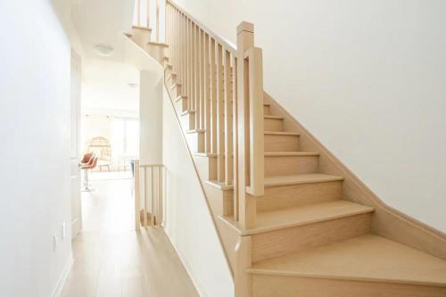 un escalier dans une maison aux murs blancs et au parquet dans l'établissement Stylish 4br Fast Wifi Sleeps 10, à Barrie