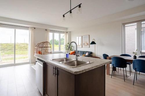 a kitchen with a sink and a table with chairs at Stylish 4br Fast Wifi Sleeps 10 in Barrie