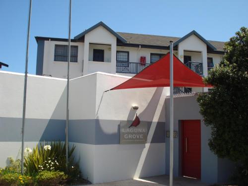 um edifício branco com um guarda-chuva vermelho em frente em Laguna Grove 14 em Knysna