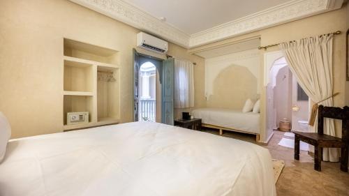 a bedroom with a large white bed and a window at Riad Luxe Nomade Marrakech & Spa in Marrakech
