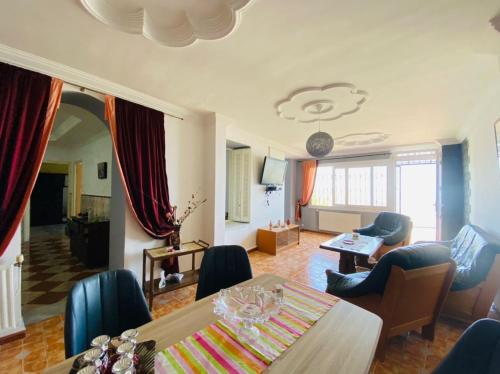 a living room with a table and chairs at Alger avec vue imprenable sur la Baie d'Alger Piscine Balcon Terrasse in El Mouradia