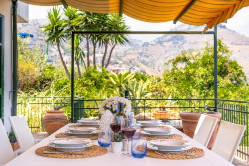 陶尔米纳La casa di Angelo的阳台上摆着盘子和酒杯的桌子
