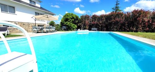 una piscina blu con ombrellone accanto a una casa di Galicia 360" a Bergondo