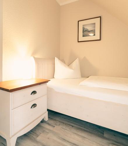 a bedroom with two beds and a nightstand with a lamp at Haus Seeschwalbe - Wohnung 13 in Spiekeroog