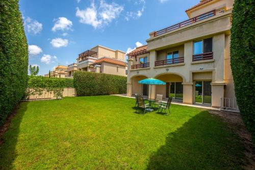 une pelouse avec des chaises et un parasol devant un bâtiment dans l'établissement Rihana Villa studios, à Borg El Arab