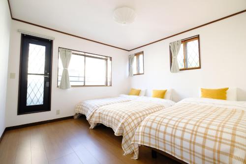 two beds in a white room with windows at Villa Hiratsuka ツバメキタル - Vacation STAY in Hiratsuka